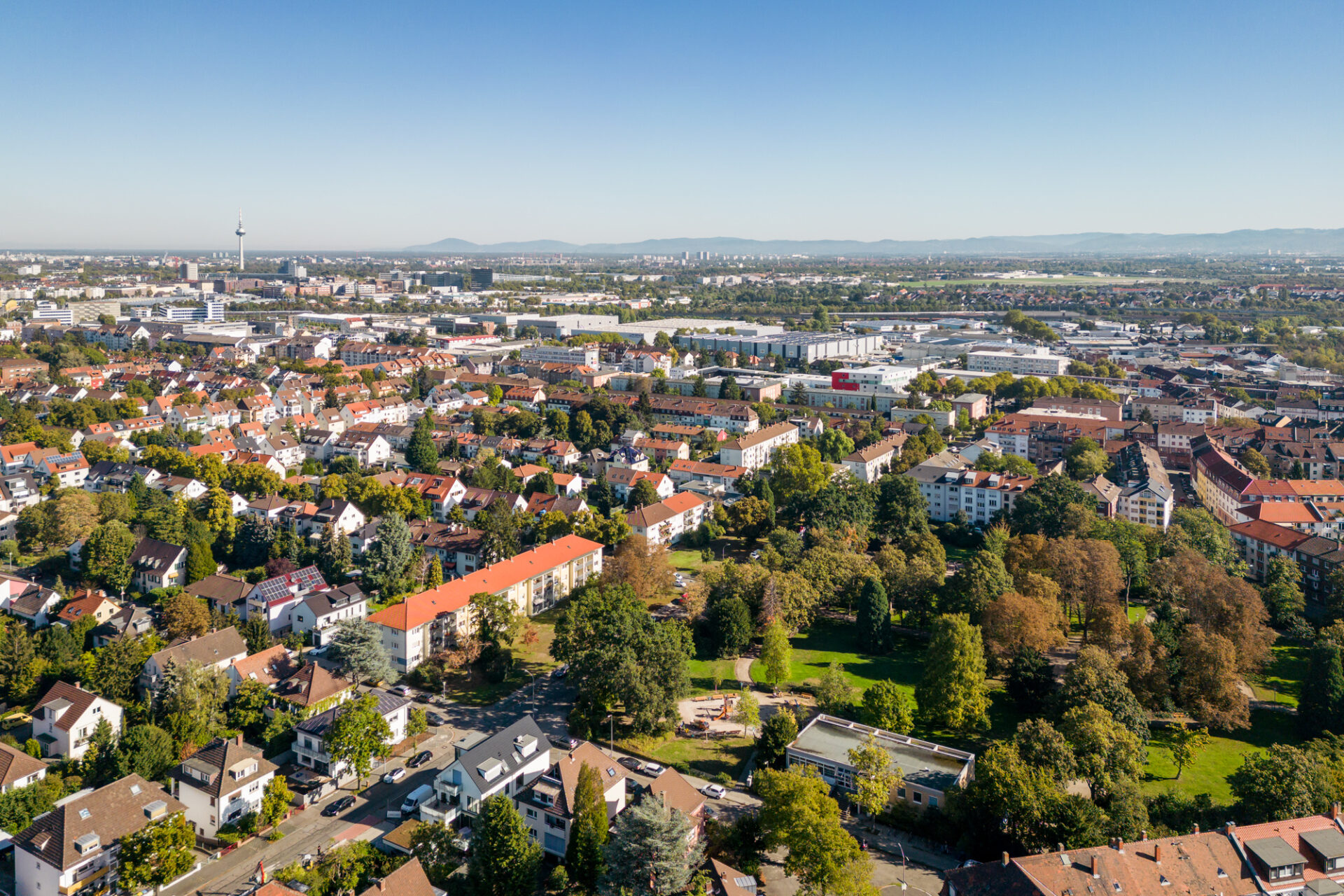 Luftaufnahme der Stadtlandschaft von Almenhof, die an einem klaren Tag dichte Wohngebiete mit modernen Gebäuden und dazwischen viel Grün zeigt.